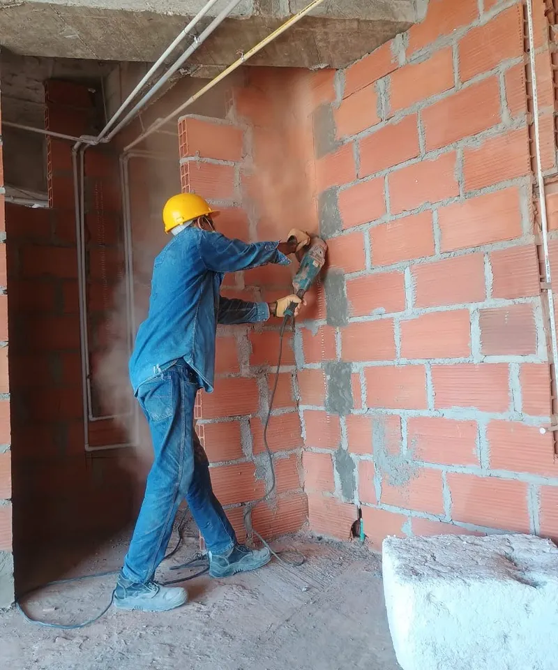 Operario de Proyecting AM perforando muro para el paso de tubería de gas